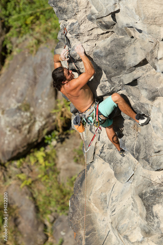 Rock climber ascending a cliff face showcasing skillful technique and physical prowess studied in sports science and outdoor recreation