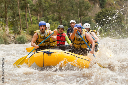 A thrilling adventure in Ecuador's whitewater river; a group of men on a white raft battling dangerous rapids, embracing the thrill and excitement.