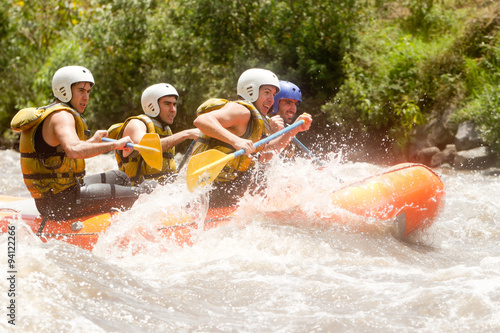 A team of rowers in Ecuador navigate a raft through the whitewater rapids of a river, competing in a thrilling rowing competition amidst the stunning nature.