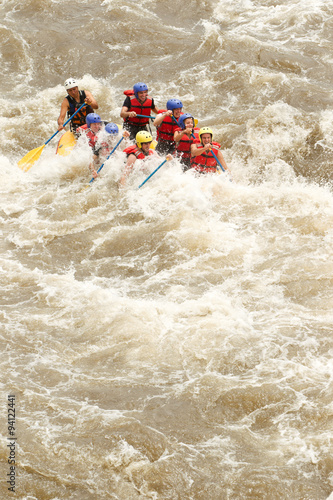 A team of rowers navigate dangerous white water rapids on a raft, with a determined woman leading the way to survival.