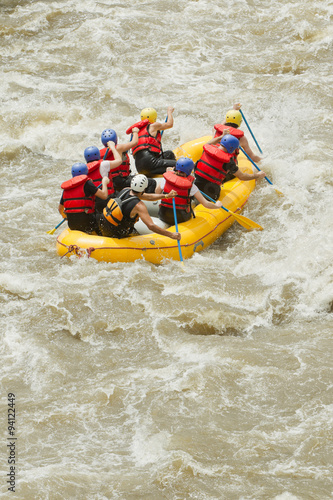 A team of women experience the power of white water rafting as they navigate through the rushing waters, feeling alive and exhilarated.