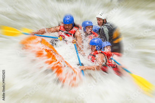 A group of adventurers navigating through the intense rapids of a white water river, feeling the rush of adrenaline on their thrilling rafting expedition. photo