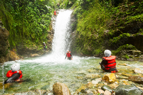 A family enjoying an action-packed outdoor adventure in Ecuador, rappelling down a waterfall, ziplining through the lush Llanganates forest and canyoning in the wet terrain. photo