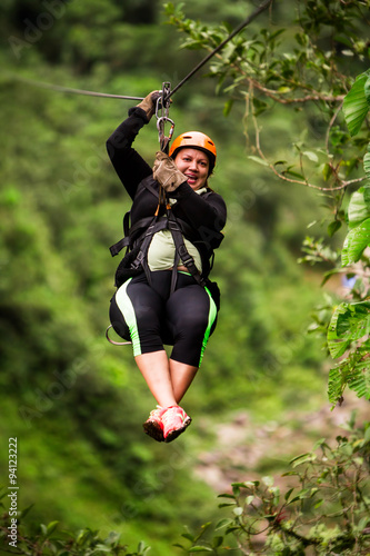 Oversized adult woman on zipline trip,enjoying an exhilarating adventure amidst the lush rainforest,captured with selective focus for a captivating visual experience.
