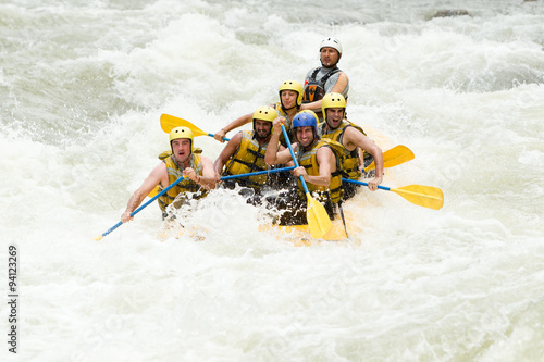 A group of extreme sports enthusiasts navigate a wild whitewater river on a white raft, guided by an experienced team in the midst of nature.