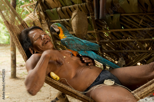 Huaorani male grooming his parrot in the Waorani Reserve,located in the biodiverse Yasuni National Park,Ecuador a stunning display of indigenous culture and wildlife conservation. photo