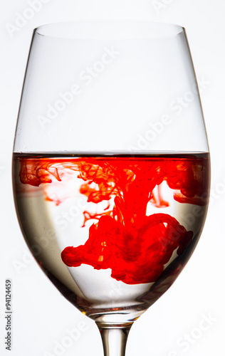 drop of red color spreading in wine glass