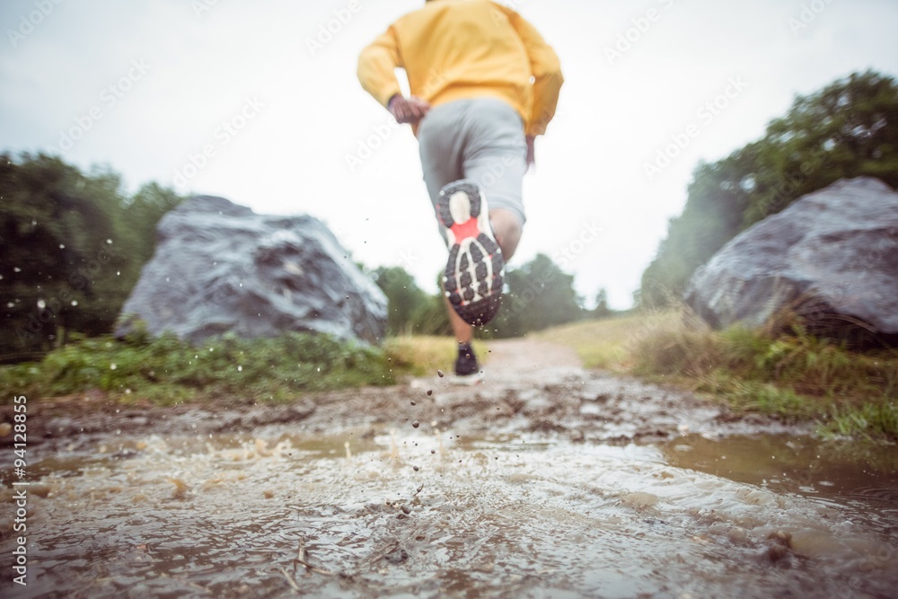 Man jogging through muddy puddles