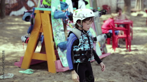 Small wakeboarder ready to start. On it the helmet and suit. photo