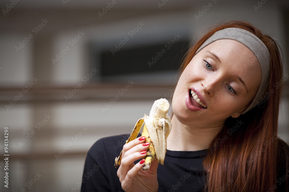 Woman is sitting in sport saloon and eating banana
