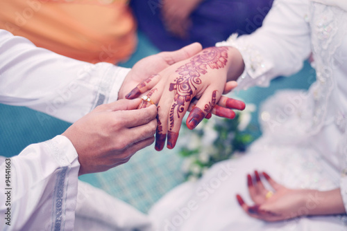 Malay Wedding Couple Putting A Gold Ring On Hand.Selective Focus © miracoure