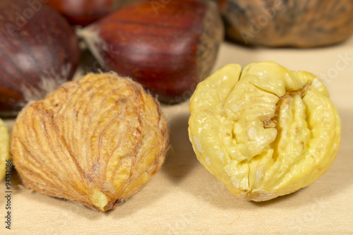 Peeled chestnuts beside other ones in shell, on a wooden table