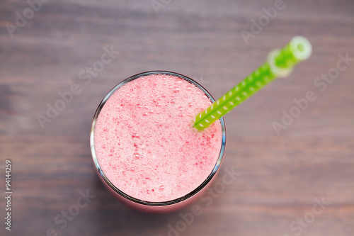 A top view of a glass of fresh watermelon smoothie on wooden background