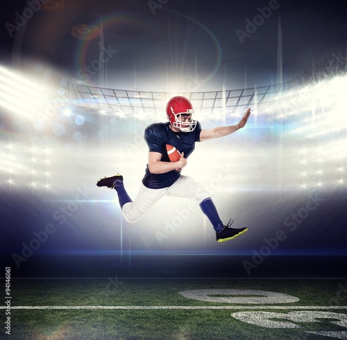 American football player jumping holding the ball