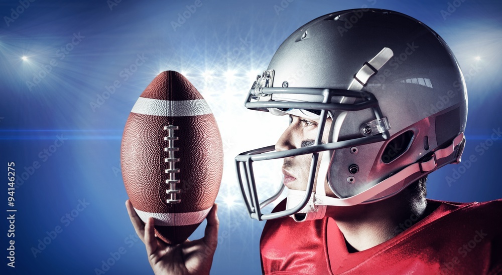 Naklejka premium American football player looking away while holding ball