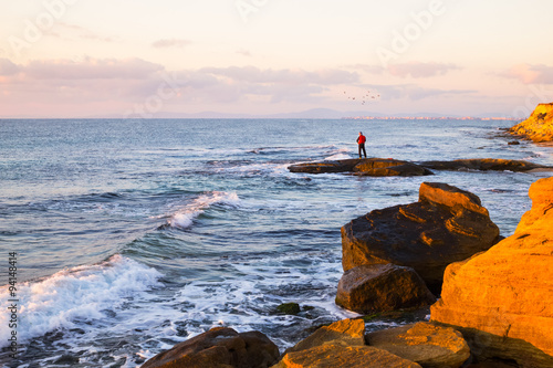 Lone fisherman fishing off rocks