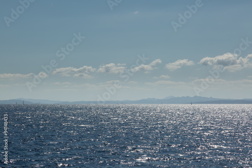 Coastline of Sardinia with several sailing boats in sunshine