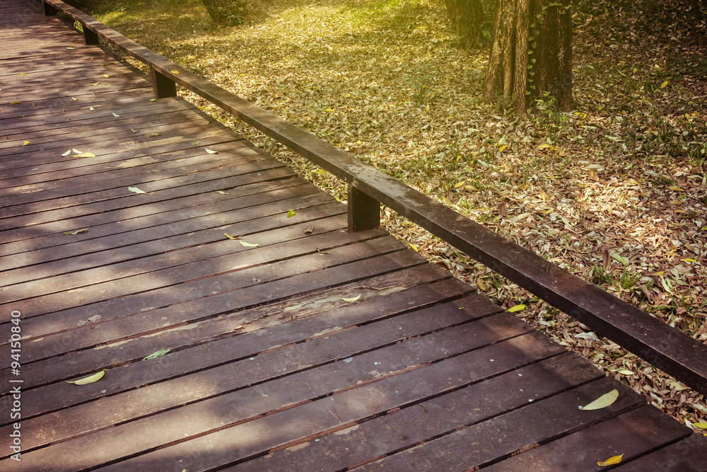 old wooden walkway with falling leaves in the morning of autumn old wooden walkway with falling leaves in the morning of autumn