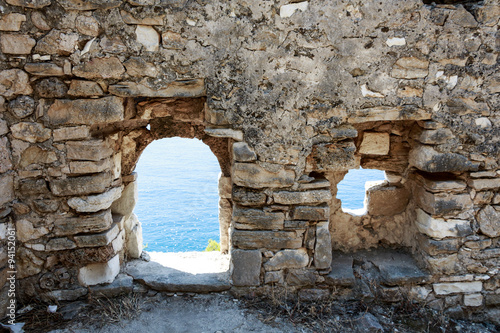 Abandoned ancient ruined wall with windows and view to the sea