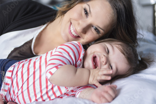 Mother and baby playing and smiling on the bedroom