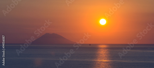 Quadro su tela Sunset over Stromboli island seen from Calabrian shore, Italy.
