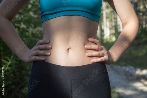 Mid section of fit woman's torso with her hands on hips. Female