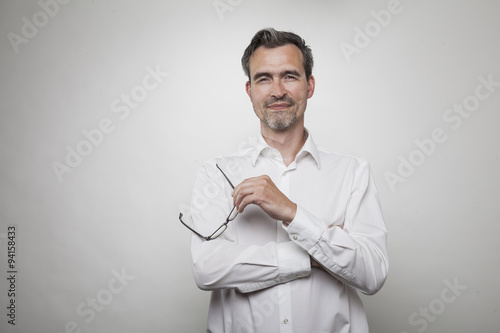 Mann im weißen Hemd mit offenem Kragen hält seine schwarze Bri