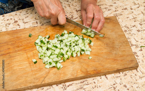 The chef cuts the cucumber on a wooden Board.