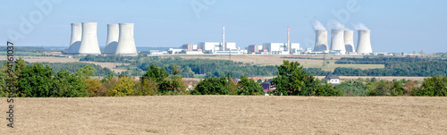 nuclear power plant against the blue sky, trees and field