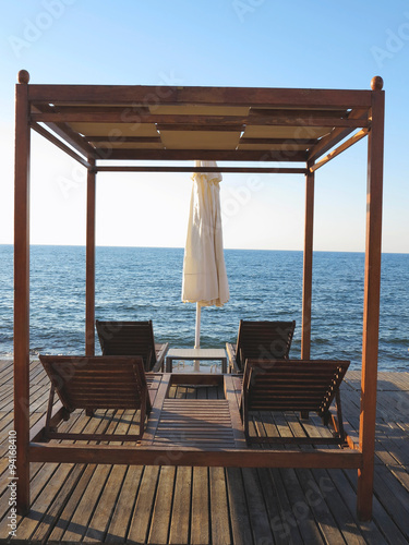 Beach chairs and umbrella on the sand near sea, blue sky © alexrow