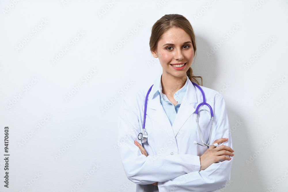Friendly smiling young female doctor, standing near wall Friendly smiling young female doctor, standing near wall