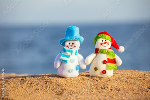 Two snowmans on sand photo