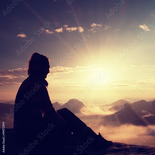 Beautiful young long hair girl tourist enjoy daybreak on the sharp corner of sandstone rock and watch over valley to Sun.