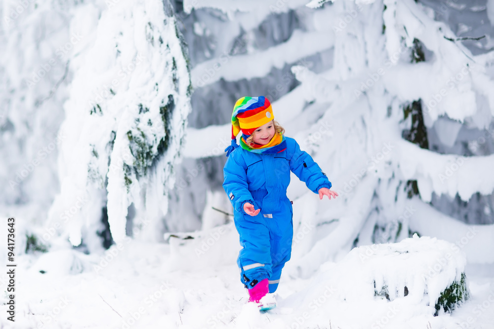 Little girl playing with snow in winter