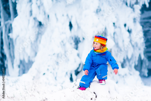 Little girl playing with snow in winter
