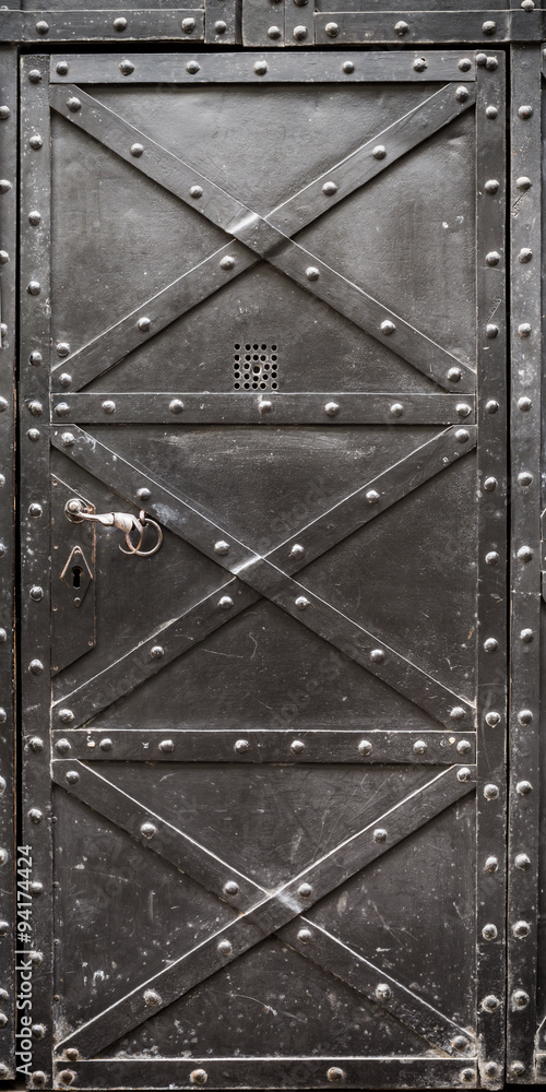 Foto de old iron door with handle, reinforced with steel belts and