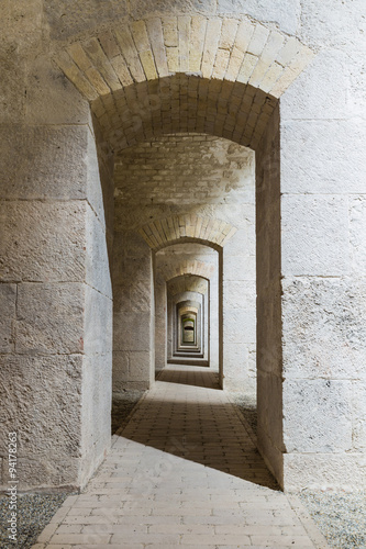 Castle tunnel interior with a series of symmetric arches in a bastion fortress. © dmpalino