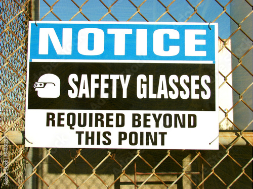 aged and worn vintage photo of safety glasses required sign