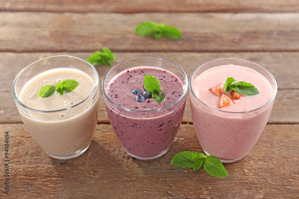 Tasty blueberry, strawberry and milk yogurts in a row on wooden background Tasty blueberry, strawberry and milk yogurts in a row on wooden background