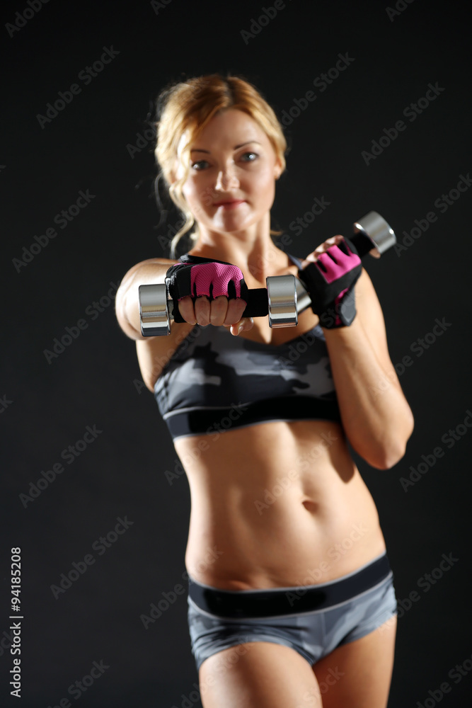 Athletic woman with dumbbell on dark background Athletic woman with dumbbell on dark background