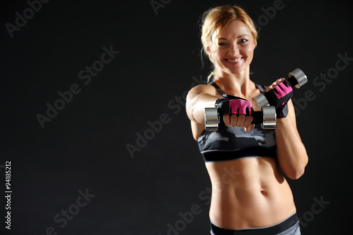 Athletic woman with dumbbell on dark background © Africa Studio