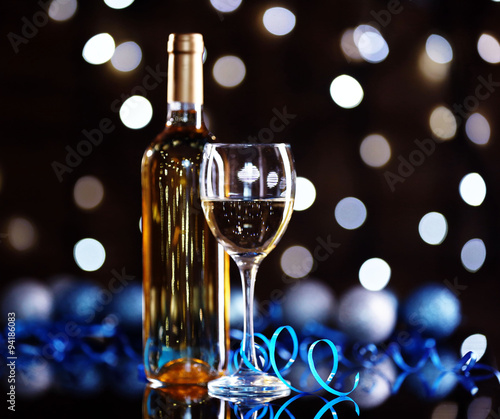 Bottle of wine and wine glass with Christmas decoration on bright background