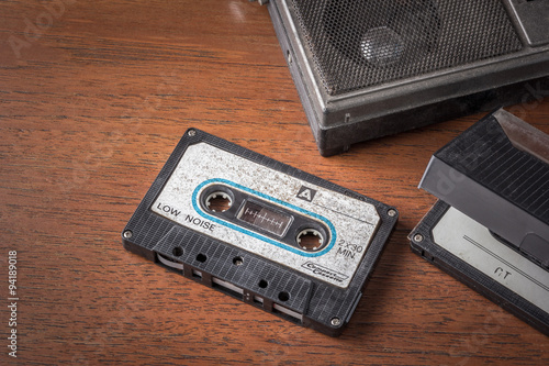 Vintage tape cassette with old radio on wooden table background
