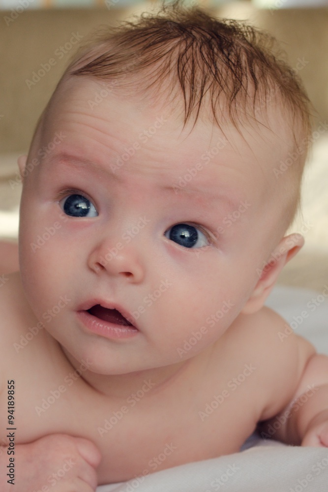 Beautiful naked baby with big blue eyes lying on the bed Beautiful naked baby with big blue eyes lying on the bed