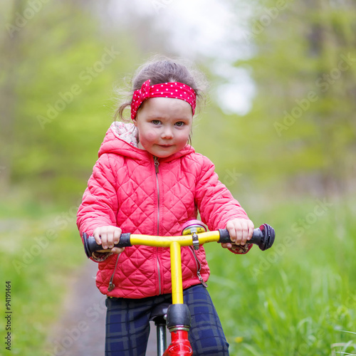 Kid girl riding his first bike, outdoors