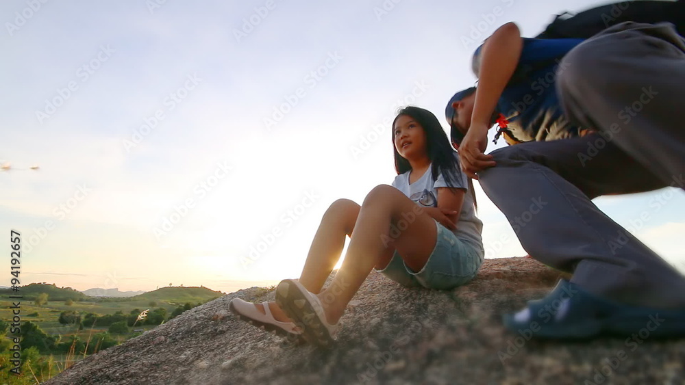 Asian children with father sitting relaxed on the mountain in Silhouette sunset time Asian children with father sitting relaxed on the mountain in Silhouette sunset time
