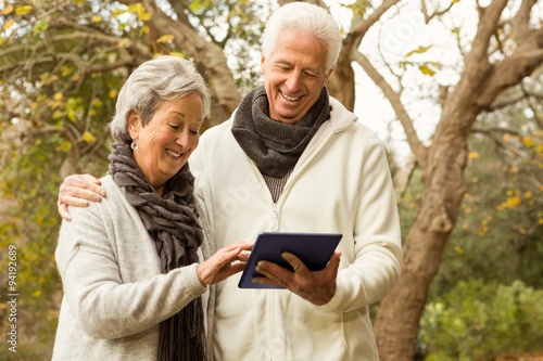 Senior couple in the park using tablet