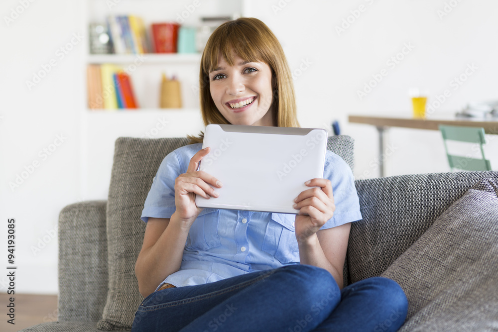 Attractive woman with digital tablet on sofa at home. Looking camera Attractive woman with digital tablet on sofa at home. Looking camera