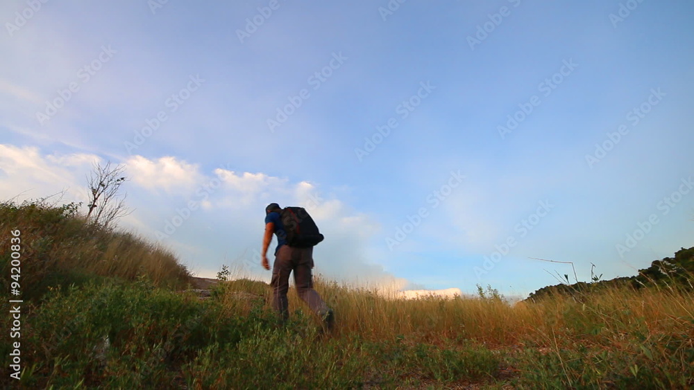 Traveler walking alone on the mountain with blue sky , Rayong province , Eastern of Thailand Traveler walking alone on the mountain with blue sky , Rayong province , Eastern of Thailand