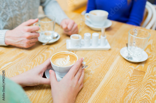 close up of hands with coffee cup at cafe